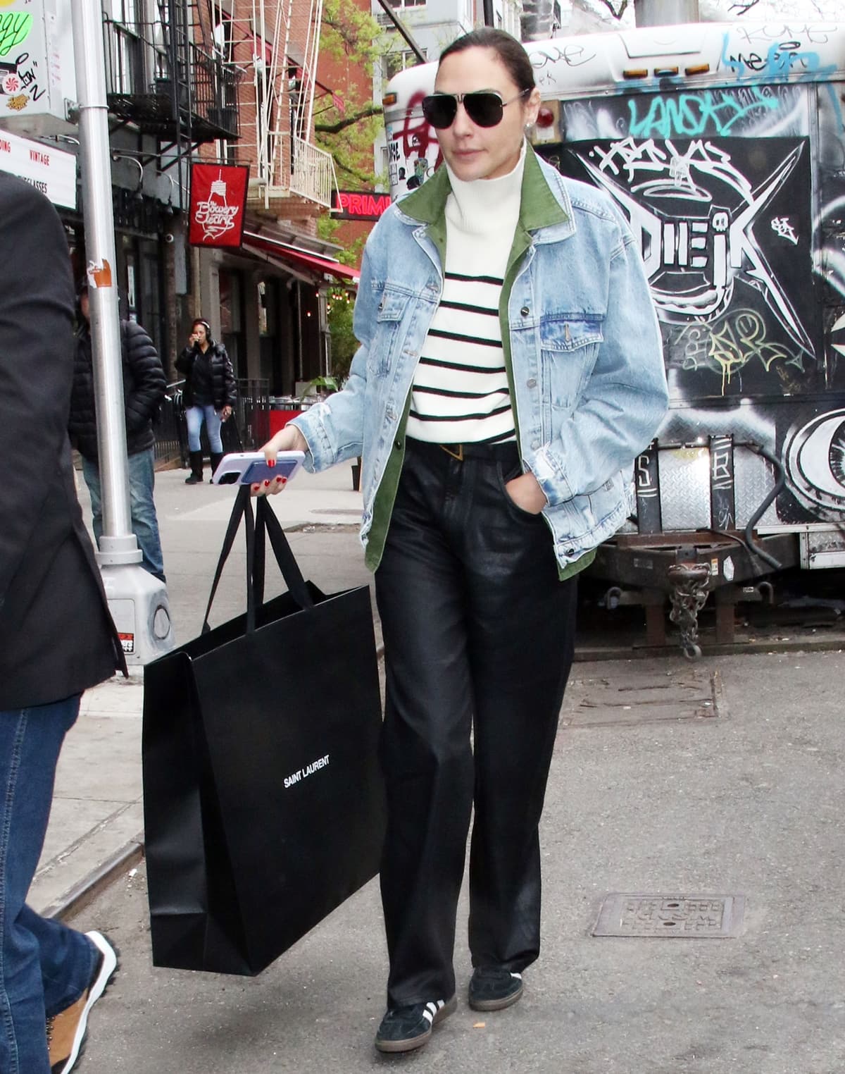 On April 28, 2023, in New York City, Gal Gadot left her hotel dressed in stylish layers, including a black and white turtleneck sweater, a khaki green overshirt, and a faded denim jacket for added warmth