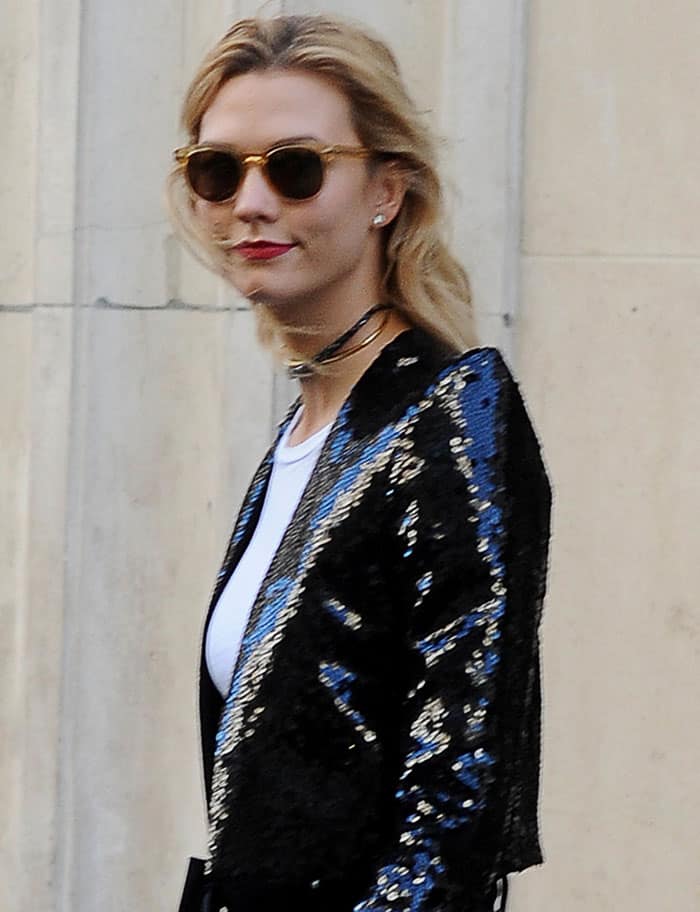 Karlie Kloss looks effortlessly stylish in her sequined jacket and sunglasses, paired with a subtle choker and a pop of red lipstick during Paris Fashion Week