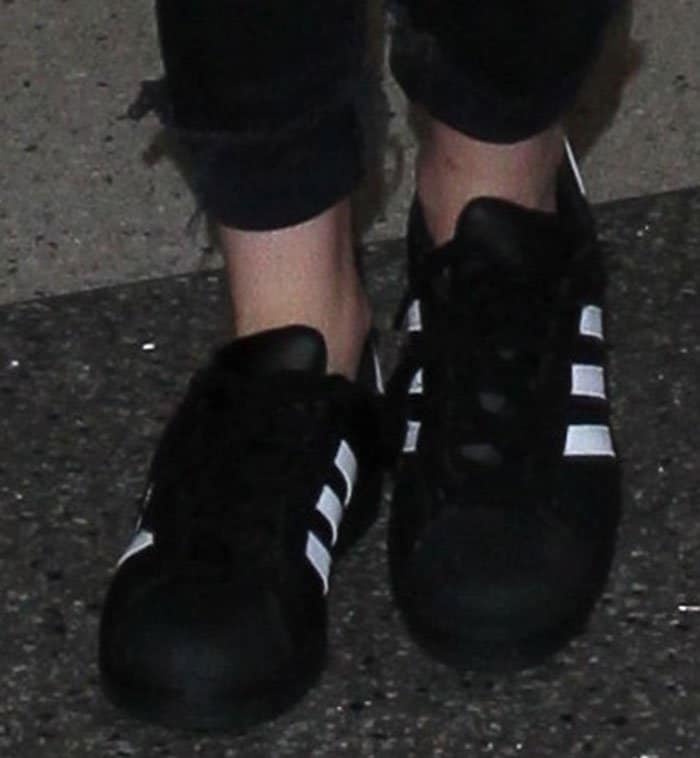 Kristen Stewart's black leather shoes are highlighted by the iconic contrasting 3-stripes design, rubber toe caps, lace-up closures, and rubber outsoles