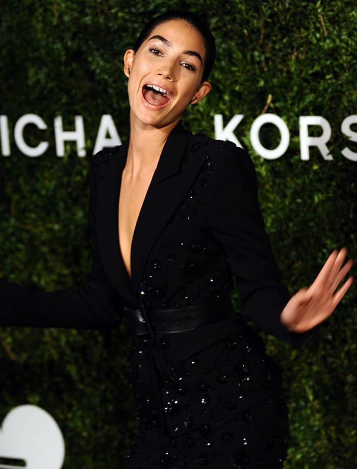 Lily Aldridge, radiating joy, playfully poses in a black, embellished Michael Kors dress