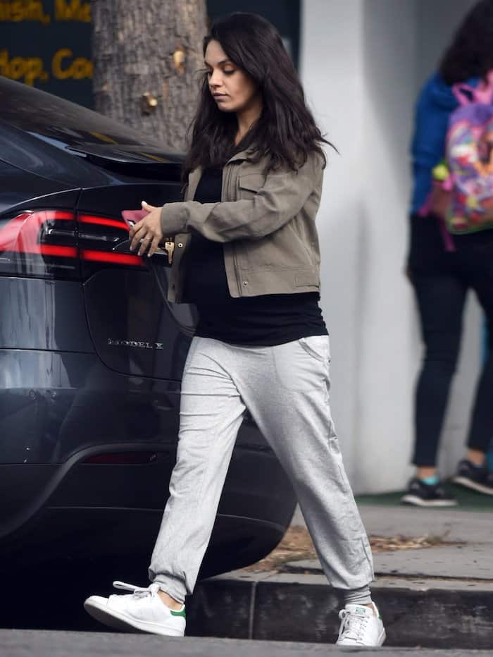Dressed in sweatpants paired with a black T-shirt and a brown jacket, Mila Kunis chose Adidas Stan Smith shoes in white and green to complete her casual attire