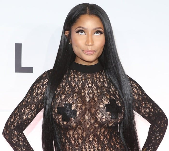 Nicki Minaj playfully poses, showing off her sleek straight hair, bold makeup, and daring lace bodysuit accented with black pasties