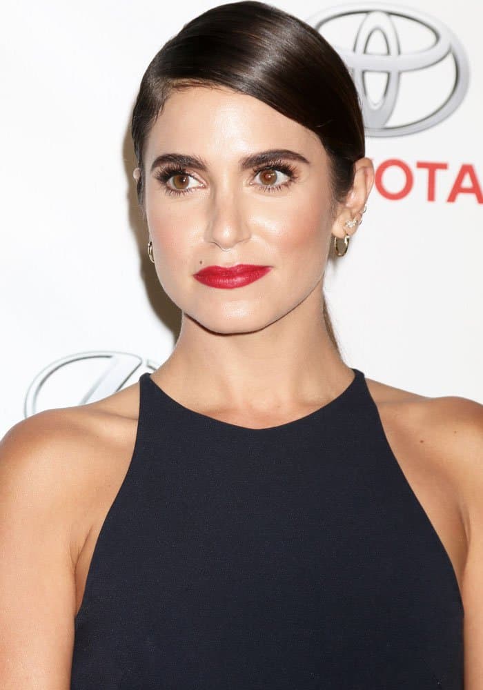 Nikki Reed exudes elegance in a sleek black halter gown, complemented by bold red lips and a polished updo at the Environmental Media Awards