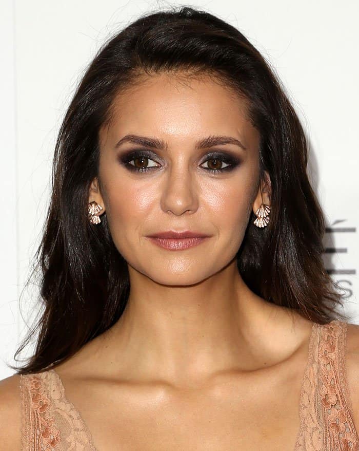 Nina Dobrev accentuated her look with dark smoky eye makeup and a dash of pink lipstick, exuding an air of timeless glamour