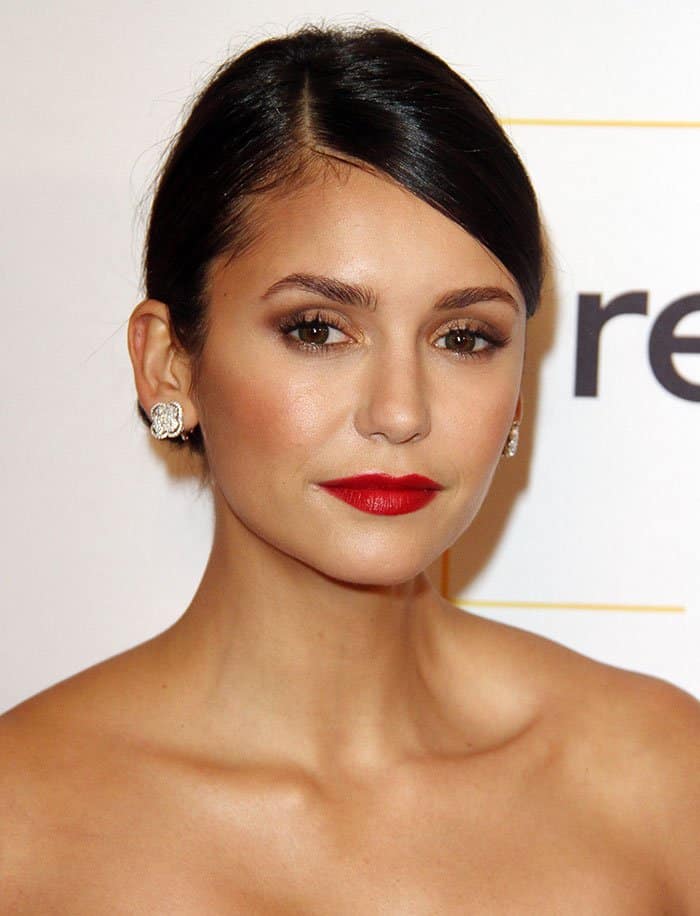 Nina Dobrev completed her look with a sleek bun and bold red lips