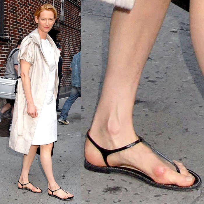 Tilda Swinton with a sore-looking bunion showing through her black t-strap sandals
