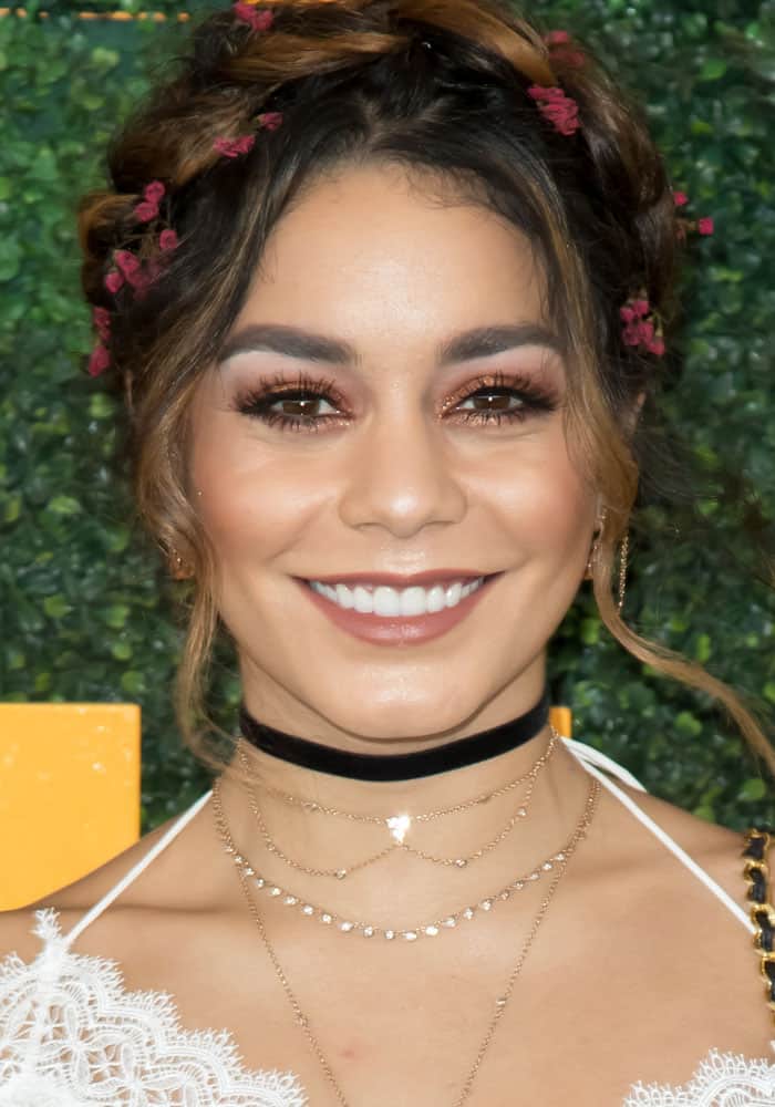 Vanessa Hudgens' hairstyle featured intricate braids adorned with tiny flowers, enhancing the overall boho vibe