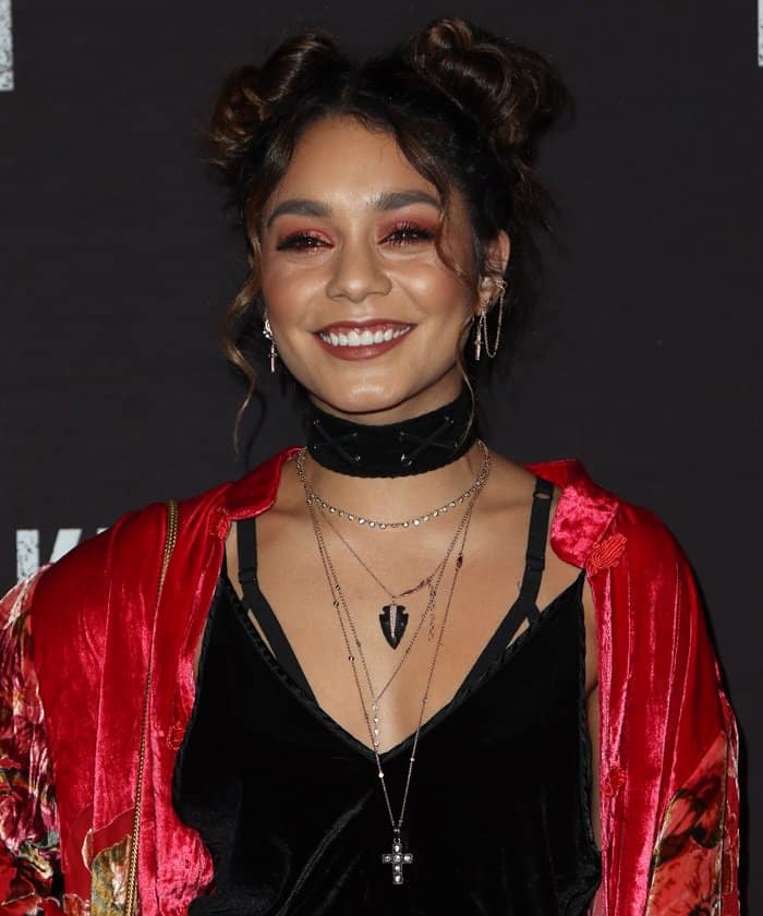 Vanessa Hudgens showcases her double bun hairstyle with bold makeup, featuring smoky eyes and a deep mauve lip
