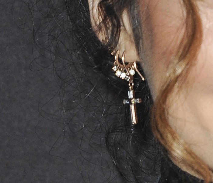Vanessa Hudgens completes her gothic look with layered earrings featuring a delicate cross charm
