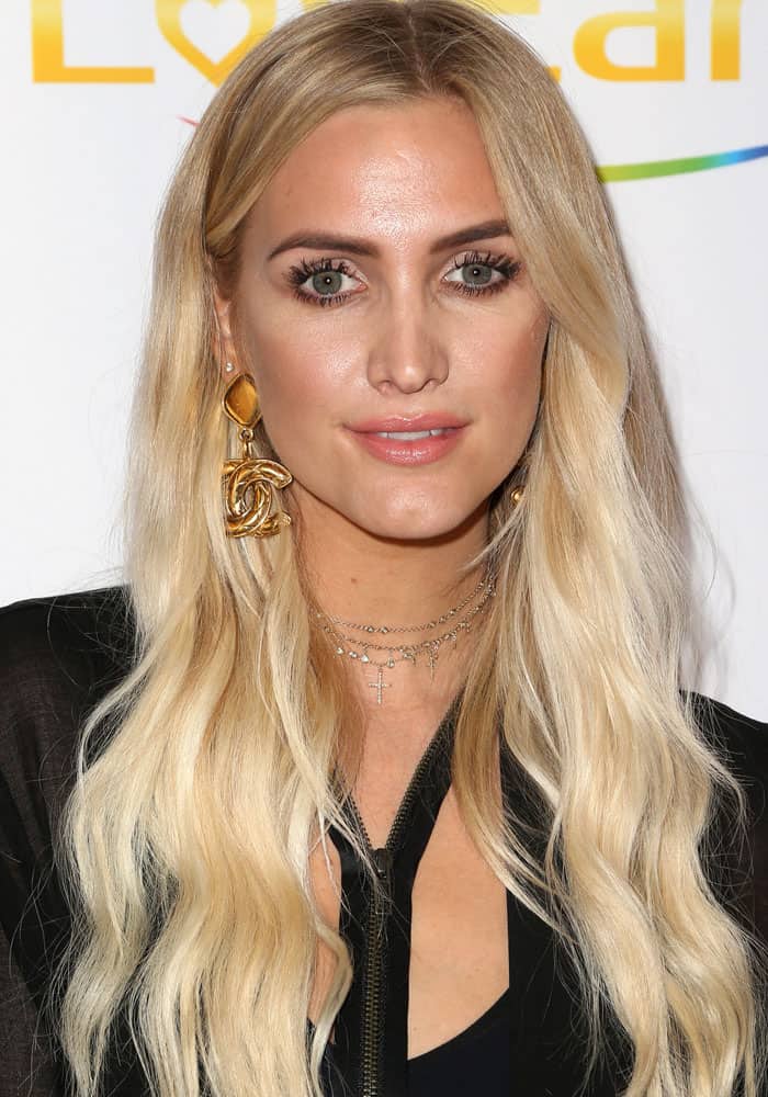 Ashlee Simpson effortlessly pairs her sleek, wavy blonde hair with bold gold jewelry, including an eye-catching Chanel earring, for a glamorous yet understated look