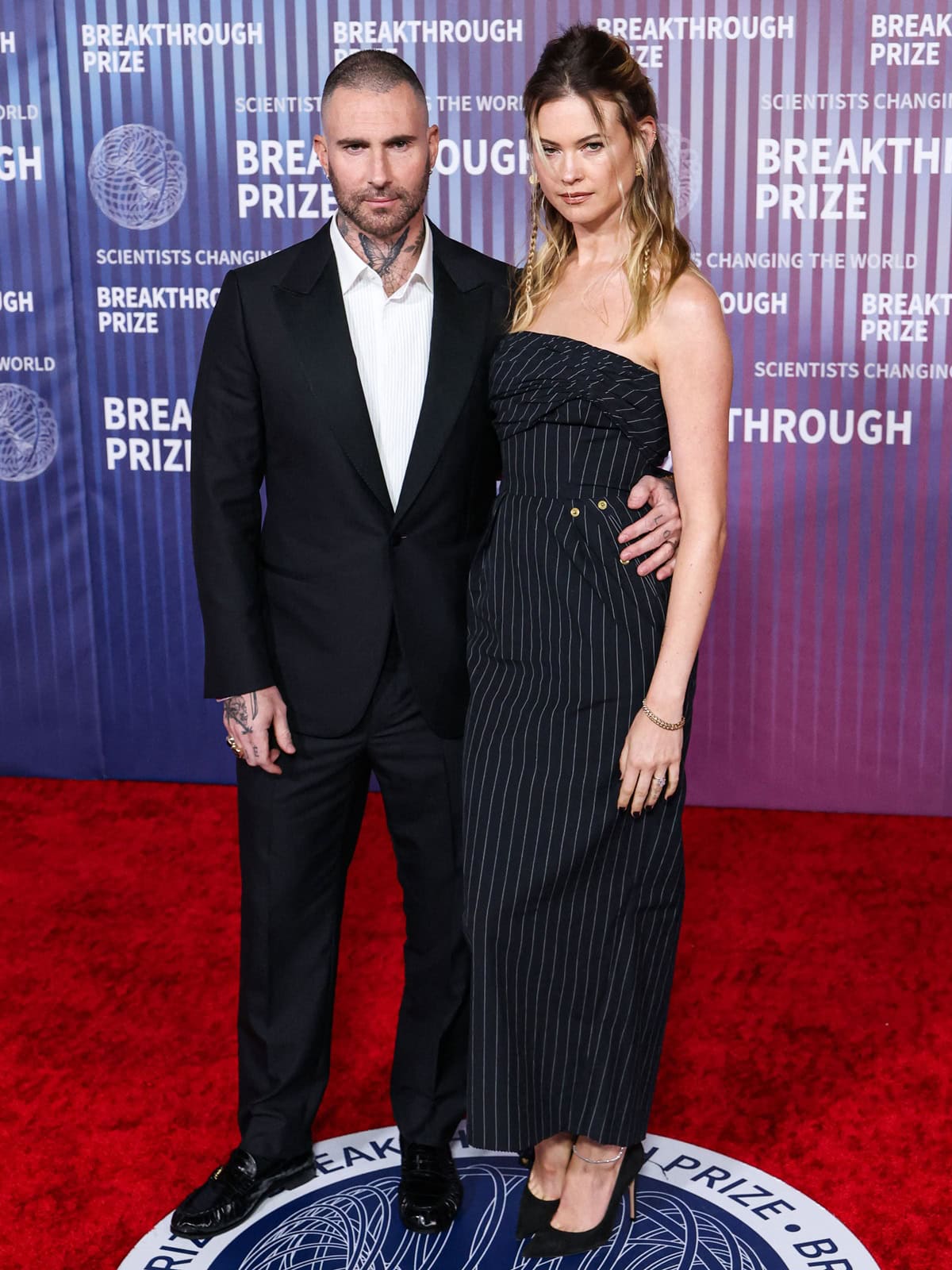 Behati Prinsloo and Adam Levine exuded coordinated elegance in black-and-white ensembles at the 10th Annual Breakthrough Prize Ceremony, with Behati stunning in a vintage Jean Paul Gaultier pinstripe gown and Adam in a classic tailored suit