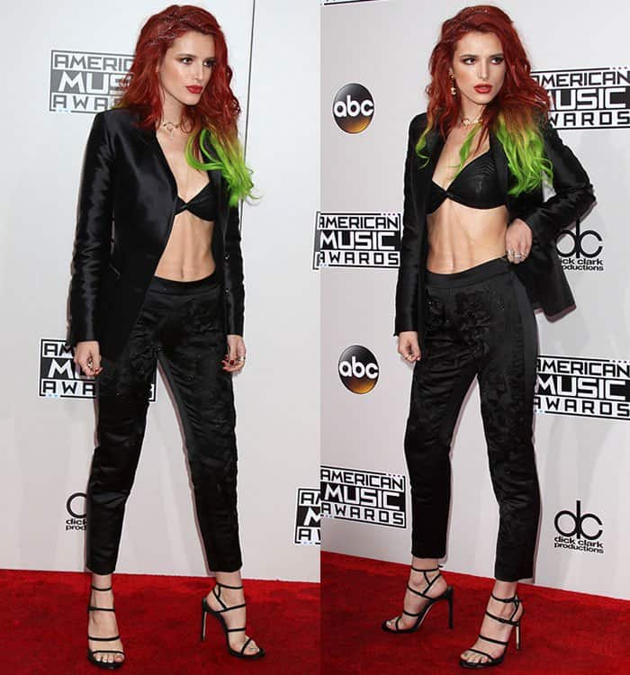 Bella Thorne wearing a black leatherette bra top, sleek jacket, and embellished pants paired with strappy Stuart Weitzman heels