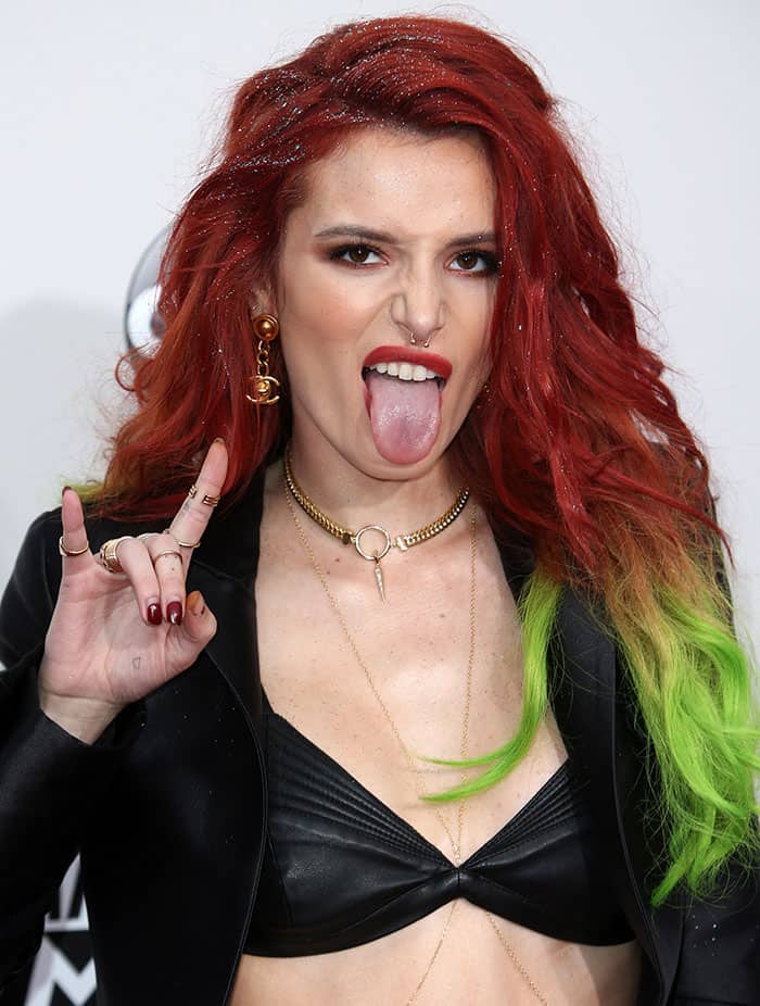 Bella Thorne showing off her septum ring and flashing the rock-and-roll hand sign with her Chanel earrings and layered gold jewelry
