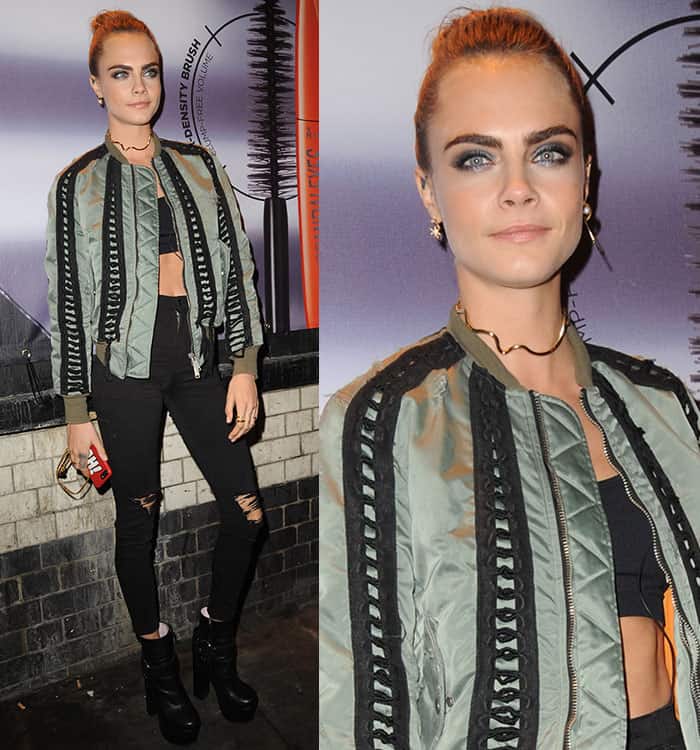 Cara Delevingne sports a bold look with a satin bomber jacket, crop top, ripped jeans, and statement platform boots, accentuated by her sleek updo and smoky eye makeup