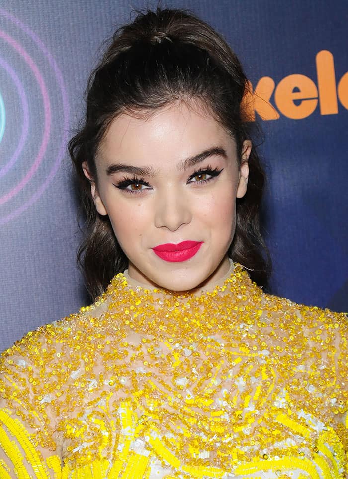 Hailee Steinfeld's makeup featured a striking pop of color with her bold matte pink lipstick, while her eyes were accentuated with dramatic black eyeliner and voluminous lashes