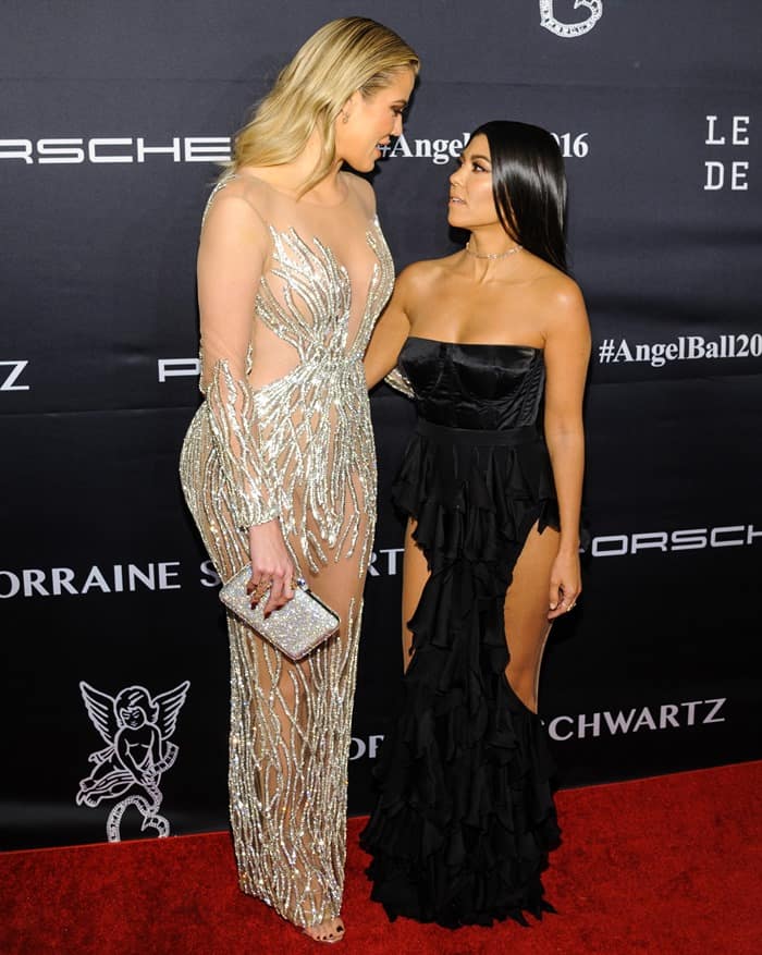 Khloe and Kourtney Kardashian highlight their striking height difference and contrasting styles at the 2016 Angel Ball, with Khloe in a sheer embellished gown and Kourtney in a chic black ruffled dress