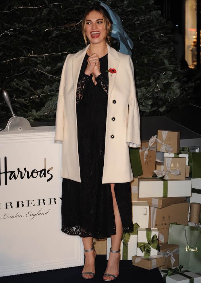 Lily James turned on the Harrods Christmas lights on November 3, 2016, in a Burberry dress and ankle-strap sandals