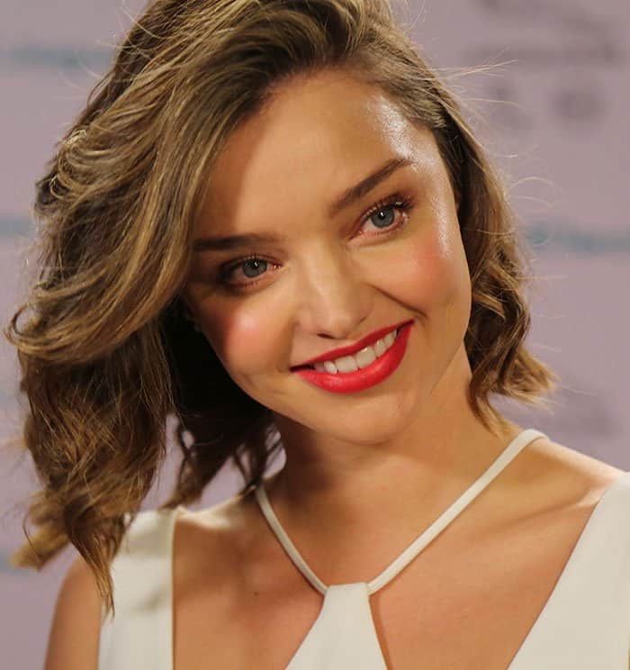 Miranda Kerr stuns with her signature side-swept tousled waves and vibrant red lipstick
