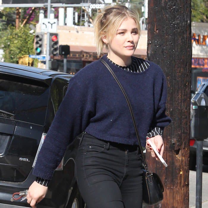 Chloë Moretz steps out in a casual chic outfit featuring a cropped navy sweater and high-waisted black jeans
