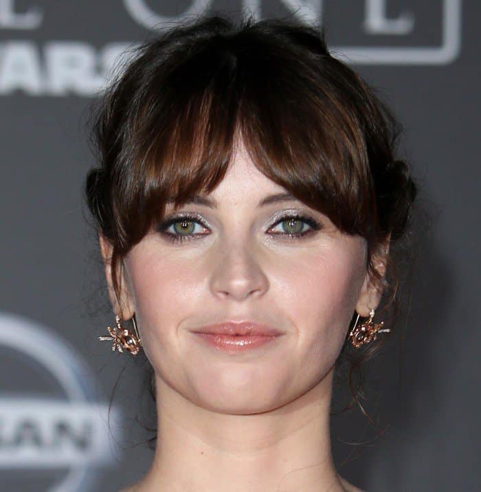 Felicity Jones styled her hair in a chic updo with soft bangs framing her face, while her sparkling star-shaped earrings added a playful yet elegant touch to her red carpet look