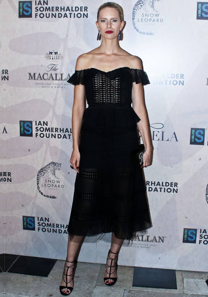 Karolina Kurkova dazzles in a chic off-the-shoulder black Johanna Ortiz dress paired with strappy Aquazzura sandals, completing her look with bold earrings and a sleek updo at the Ian Somerhalder Foundation Gala