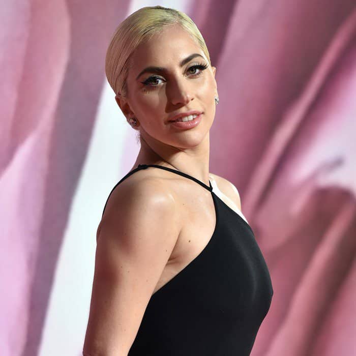 Lady Gaga complements her sleek hairstyle with a soft nude lip and elegant diamond stud earrings