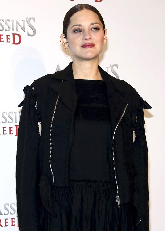 Marion Cotillard showcases a sleek, center-parted ponytail with a statement hoop earring at the Assassin's Creed Berlin photo call