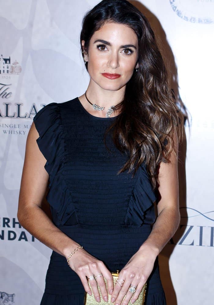 Nikki Reed complements her elegant waves with a gold textured clutch, adding a touch of glam to her dark ensemble at the Ian Somerhalder Foundation Benefit Gala