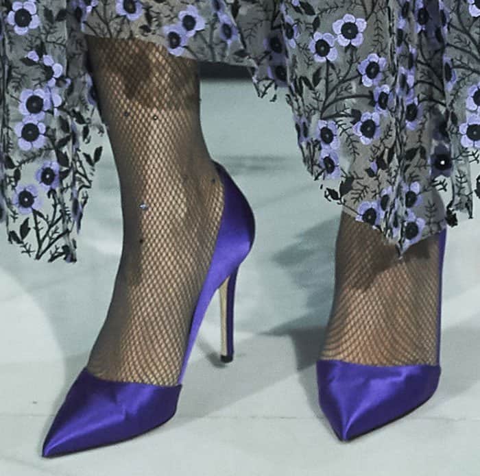 Sarah Jessica Parker paired her ensemble with sheer fishnet stockings, adding texture to her look, and completed it with her striking purple satin SJP "Rampling" pumps