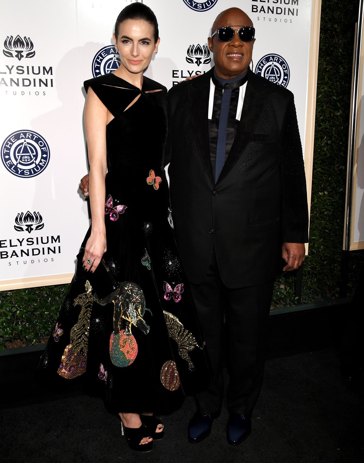Camilla Belle and Stevie Wonder attend the 10th annual Art of Elysium "Heaven" Gala, celebrating the organization's 20th anniversary, with Belle wearing an elegant, embroidered gown
