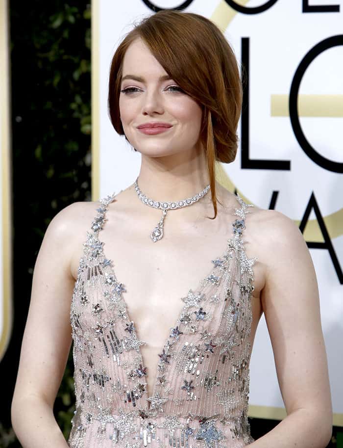 Emma Stone exudes vintage glamour with a sleek updo, delicate diamond necklace, and a Valentino gown adorned with sparkling star embellishments