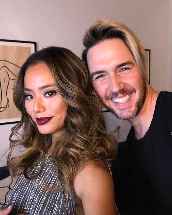 Jamie Chung poses with her hairstylist Paul Norton, showcasing her glamorous waves and bold makeup look