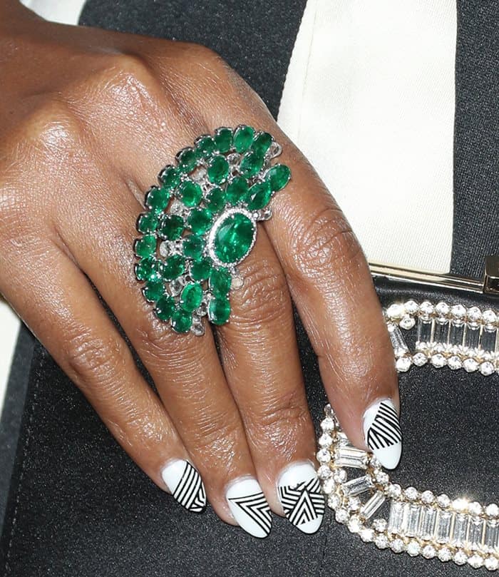 Janelle Monáe's emerald ring mirrored the intricate craftsmanship of her earrings, while her bold black-and-white geometric manicure tied seamlessly to her gown's striped design for a cohesive and striking look
