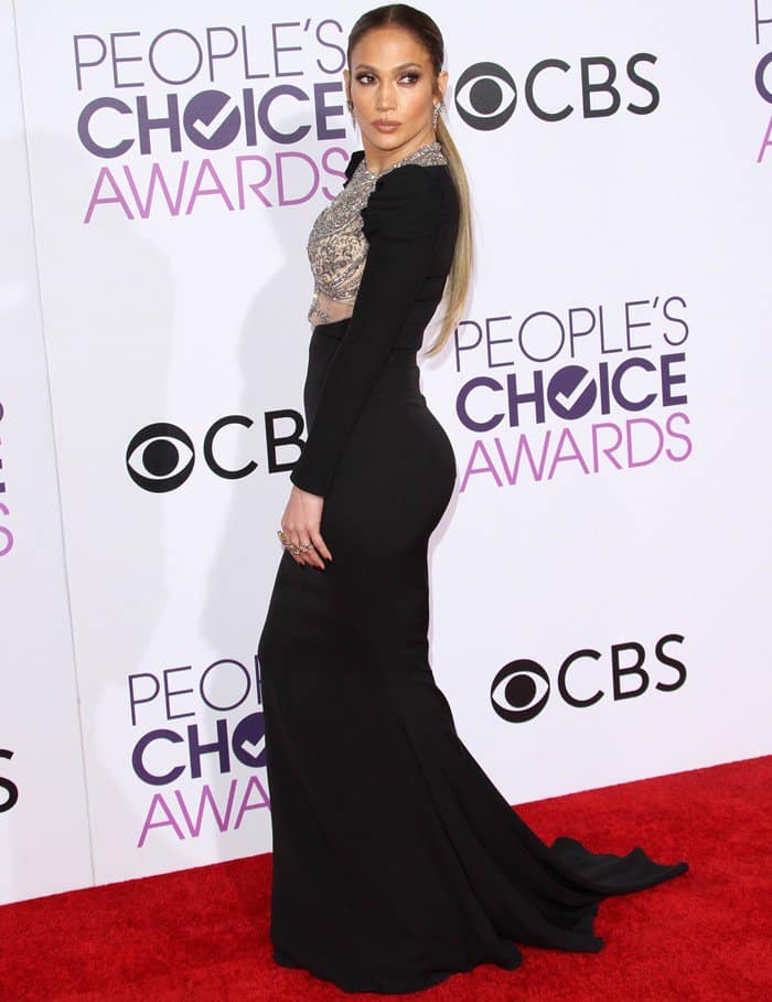 Jennifer Lopez exuded elegance in a black Reem Acra gown with a fitted silhouette, intricate embellishments, and a floor-length train, creating a stunning red-carpet look