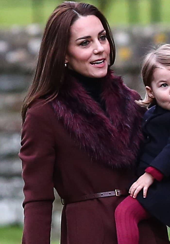 Kate Middleton steps out in a chic maroon coat paired with a faux fur collar, exuding winter elegance while attending Christmas Day services with her family