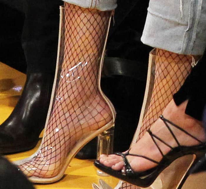 Kendall Jenner's daring look features clear PVC boots, showcasing fishnet socks while hinting at the challenges of keeping feet cool in the stylish, yet sweat-inducing, design