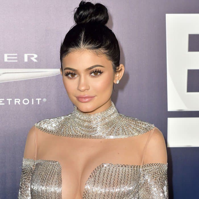 Kylie Jenner showcases a sleek updo, flawless makeup, and diamond earrings