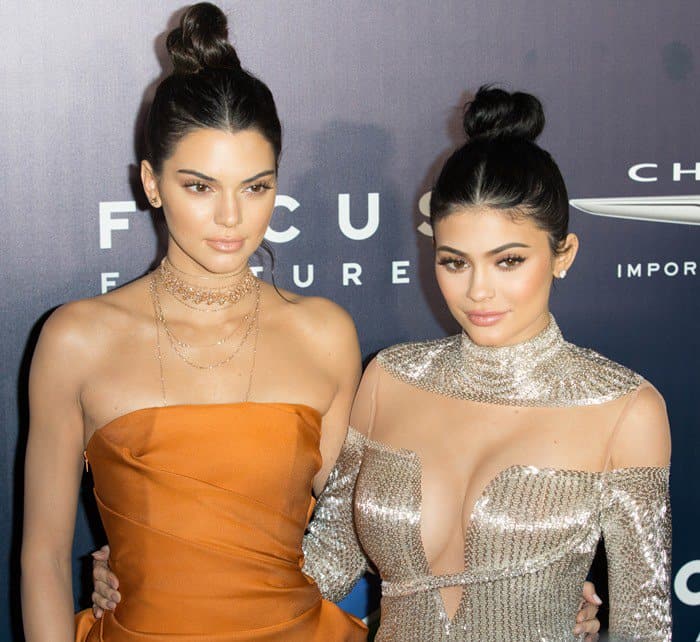 Kendall and Kylie Jenner showcase contrasting styles, with Kendall in a sleek orange gown and Kylie in a sparkling silver ensemble