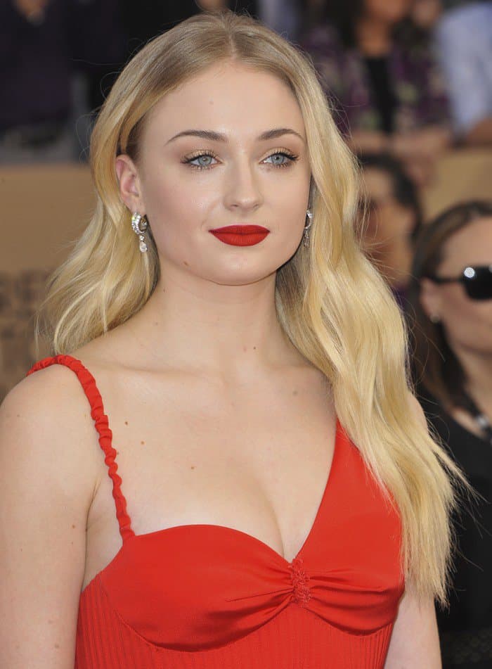 Sophie Turner stunned with dazzling drop earrings that added sparkle to her custom red Louis Vuitton dress, featuring delicate ruched details and a flattering sweetheart neckline