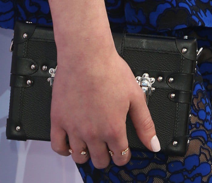 Sophie Turner added a touch of elegance to her outfit with a structured black clutch and dainty gold rings, complemented by her chic white manicure