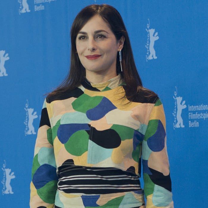 Amira Casar attends the 67th Berlin International Film Festival in Berlin, Germany, on February 13, 2017, wearing a sleek side-parted hairstyle and understated makeup with a bold red lip that complements her vibrant Marni dress
