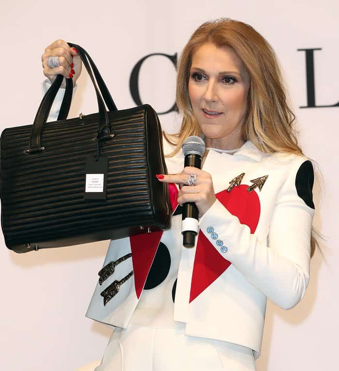 Céline Dion proudly showcases one of her handbags from the new collection at the Project Women’s trade fair