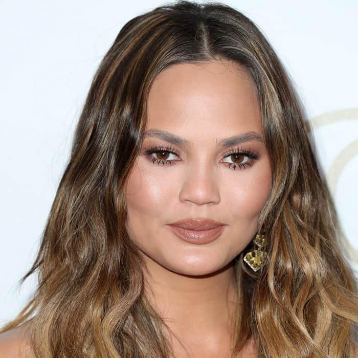 Chrissy Teigen showcased soft, loose waves paired with warm-toned makeup and gold statement earrings