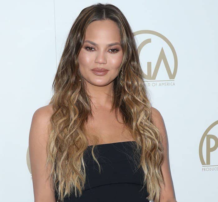 Chrissy Teigen stunned with dewy makeup featuring bronzed tones and nude lips, perfectly complementing her strapless midnight blue dress