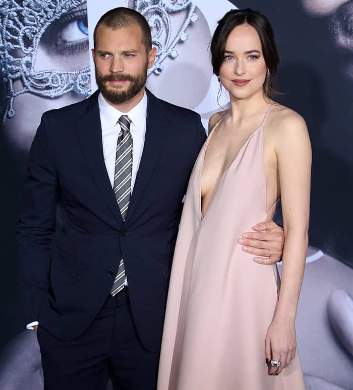 Dakota Johnson exudes timeless elegance in a plunging blush gown, perfectly complemented by Jamie Dornan's sharp navy suit, making them a striking duo on the red carpet