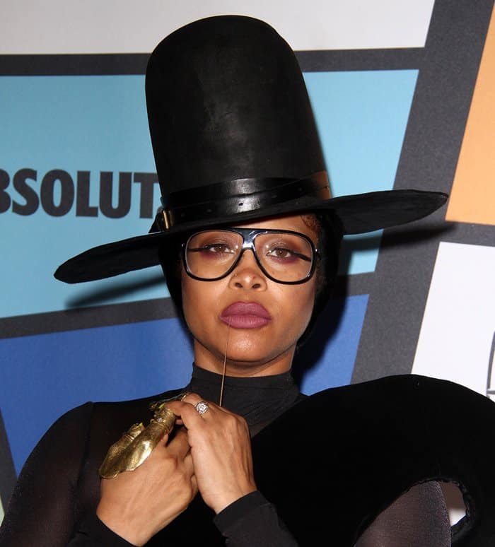 Erykah Badu completes her look with a large, dramatic black hat that adds a bold, whimsical flair