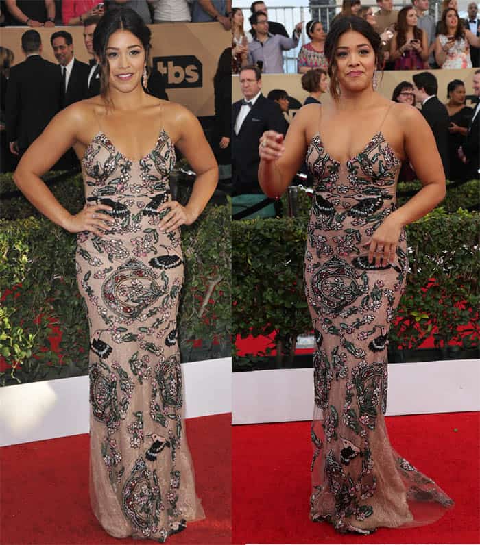 Gina Rodriguez shines in a figure-hugging embroidered gown with intricate patterns and delicate straps, exuding confidence and glamour on the red carpet