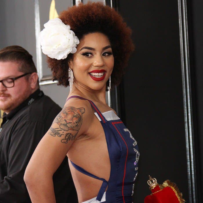 Joy Villa complements her afro hairstyle adorned with a white flower and showcases her bold tiger tattoo