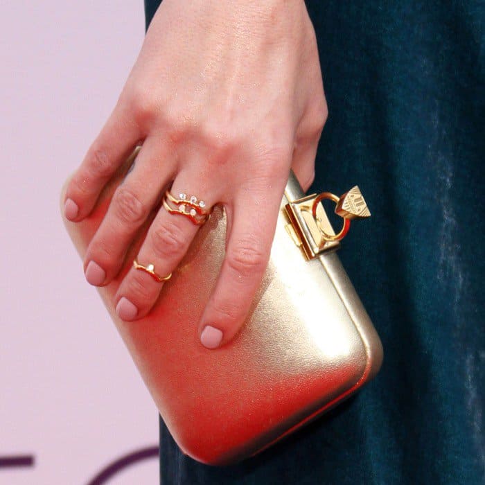 Keltie Knight's elegant gold clutch is complemented by delicate stacked rings and a soft nude manicure