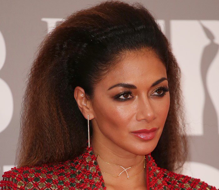 Nicole Scherzinger dazzles with her voluminous crimped hairstyle and minimalist jewelry, featuring a delicate gold necklace and drop earrings